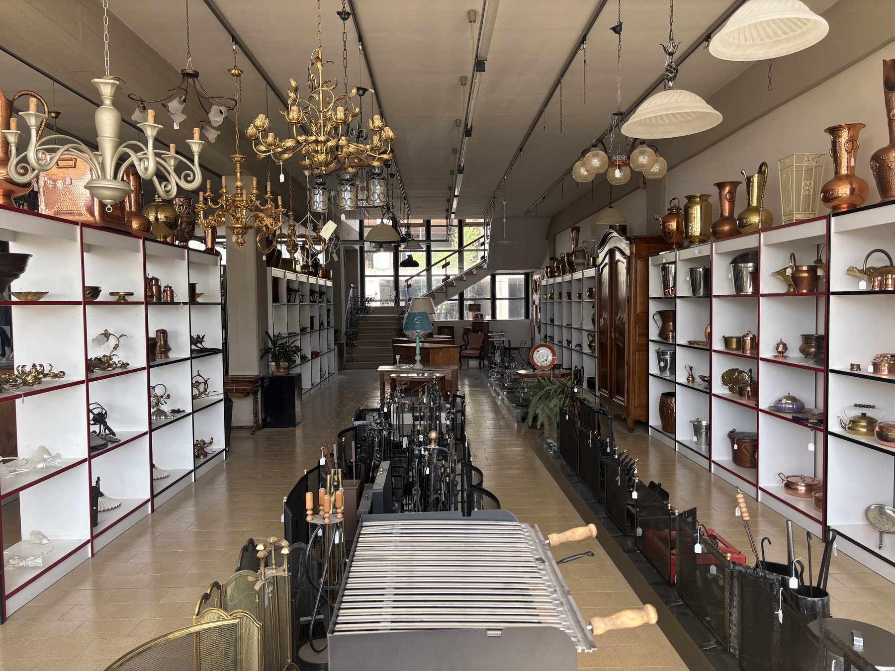 Corridoio dello showroom Angelini con lampadari in ottone e vetrine di rame