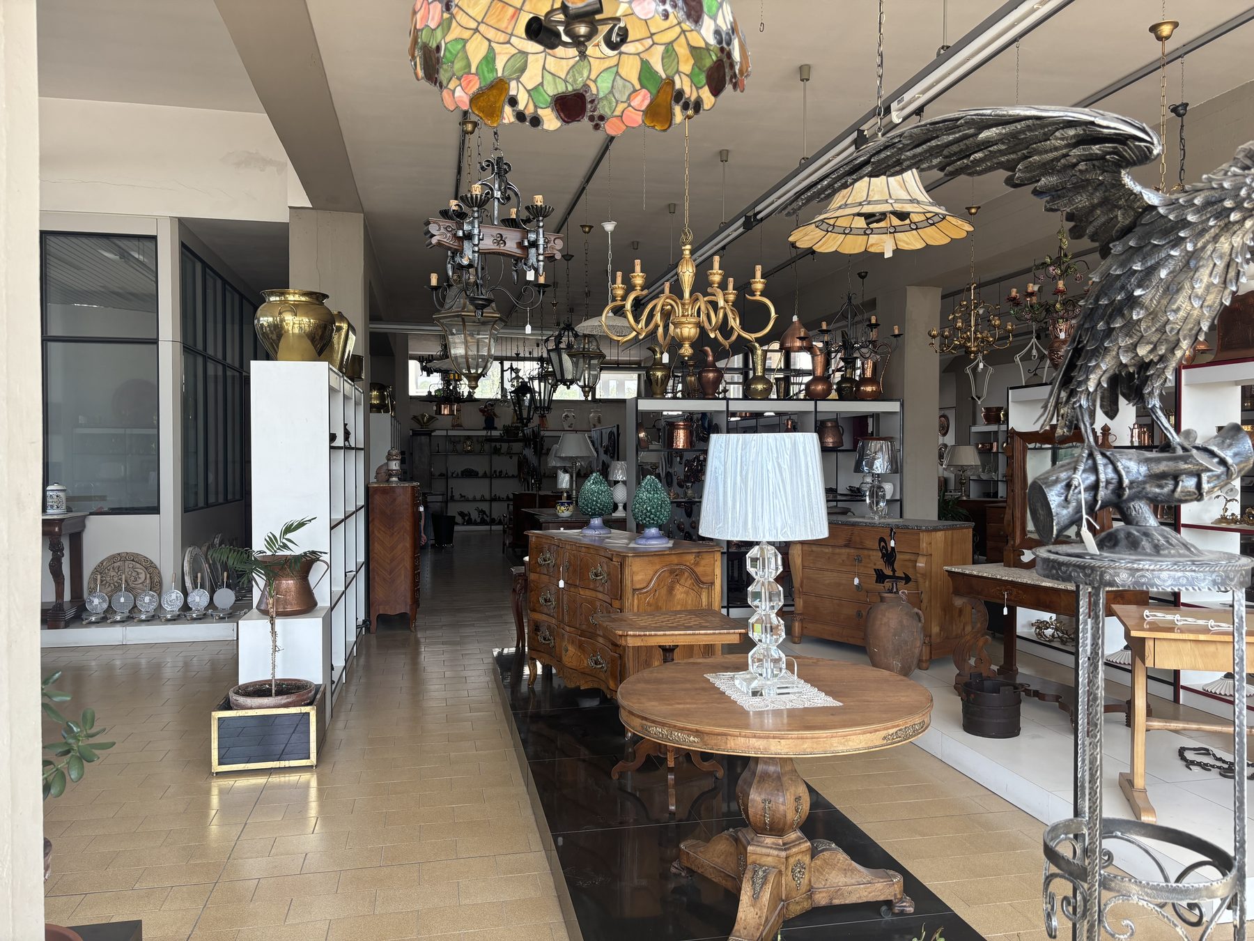 Showroom Angelini con lampade Tiffany, lampadari dorati e scultura in metallo