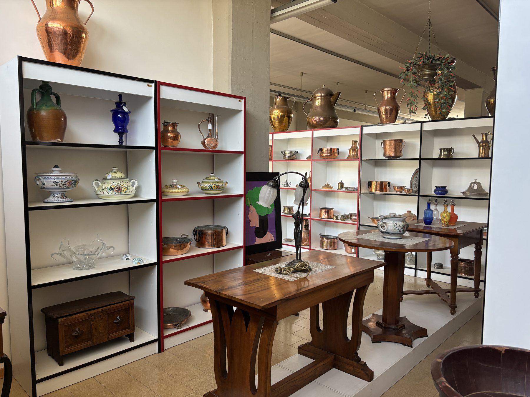 Scaffali dello showroom Angelini con ceramiche, rame e oggetti d'arte