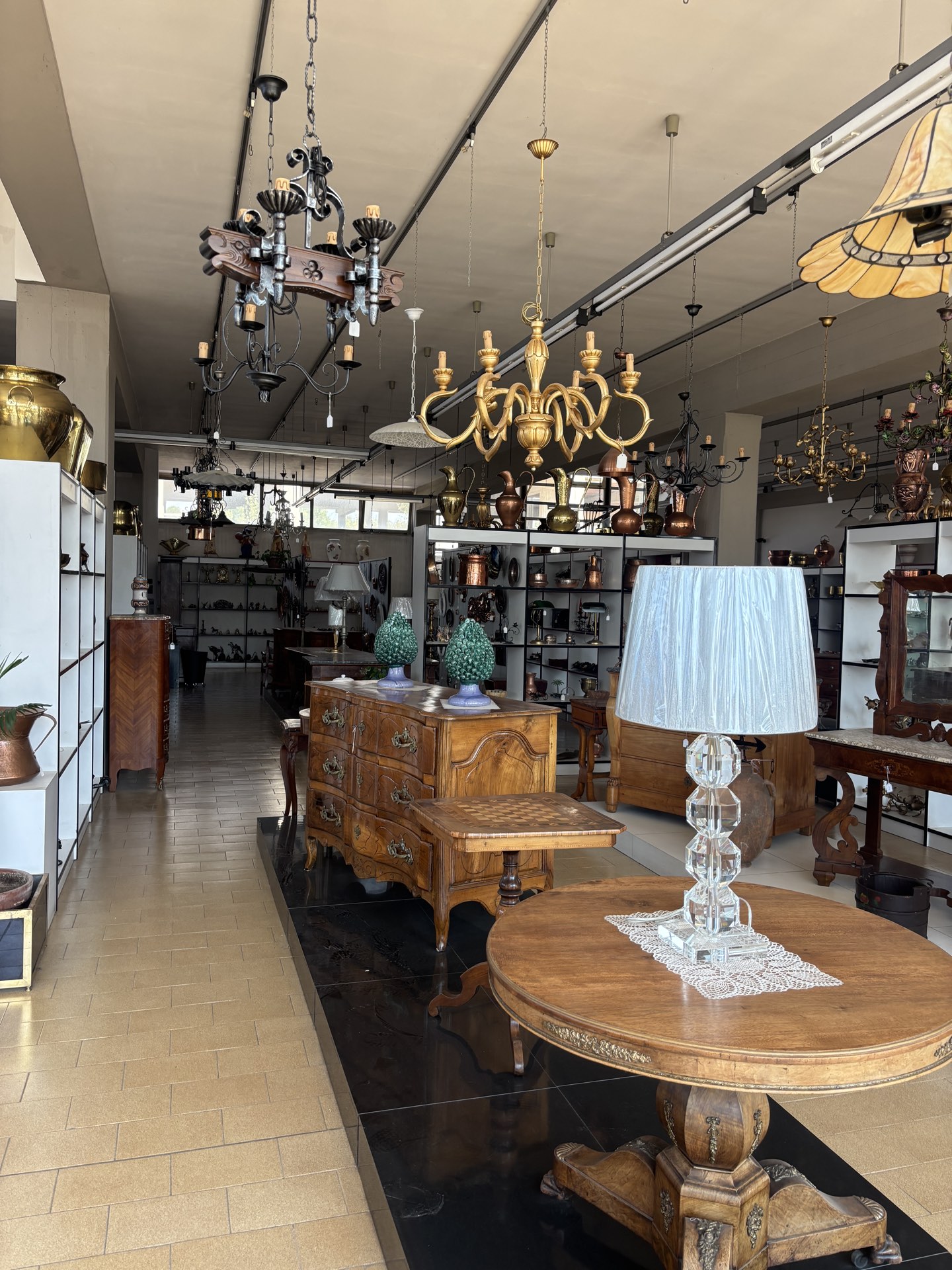 Vista panoramica dello showroom Angelini con lampadari antichi e comò d'epoca